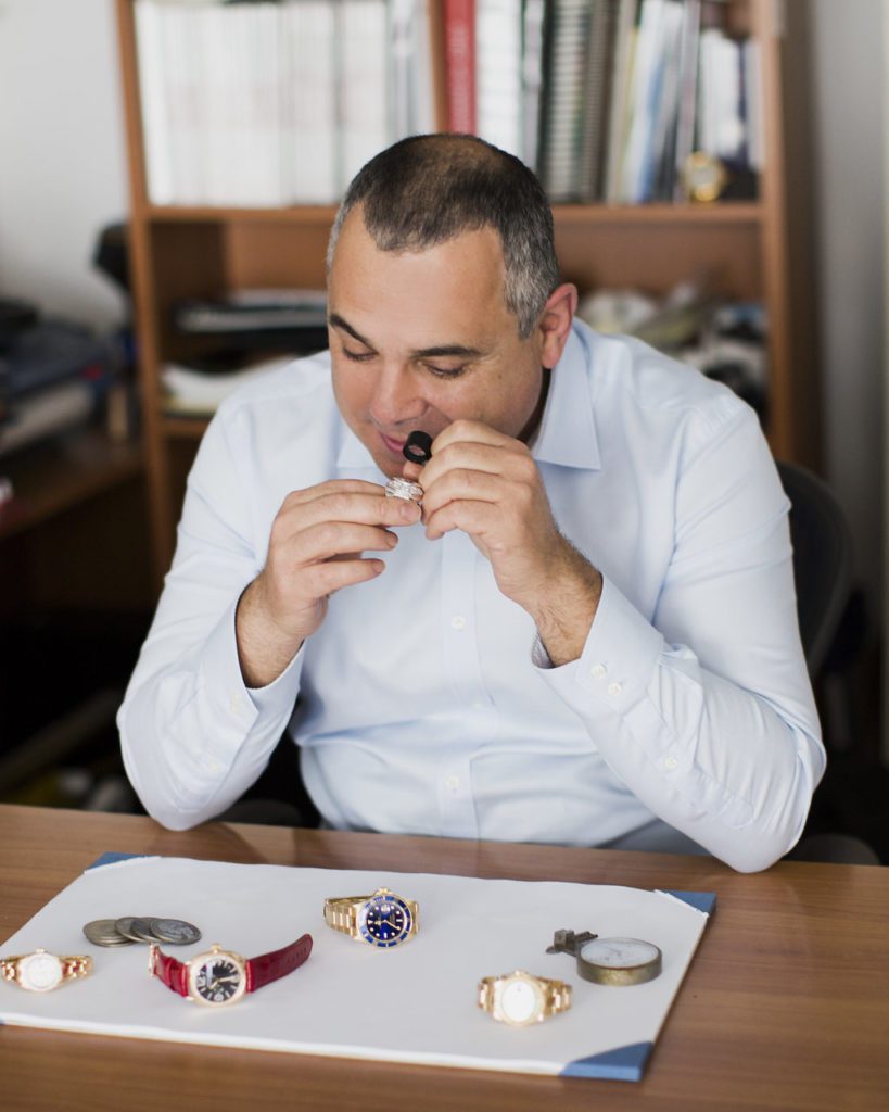 Image of the owner evaluating jewelry at his desk.