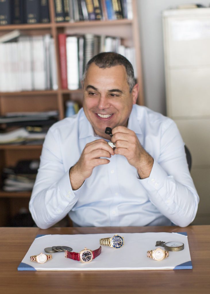 Image of the owner smiling while evaluating jewelry at his desk.