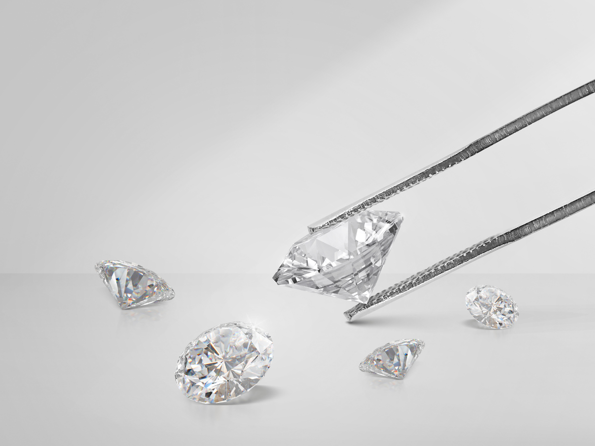 Loose diamonds being held by jeweler's tweezers, selling diamonds